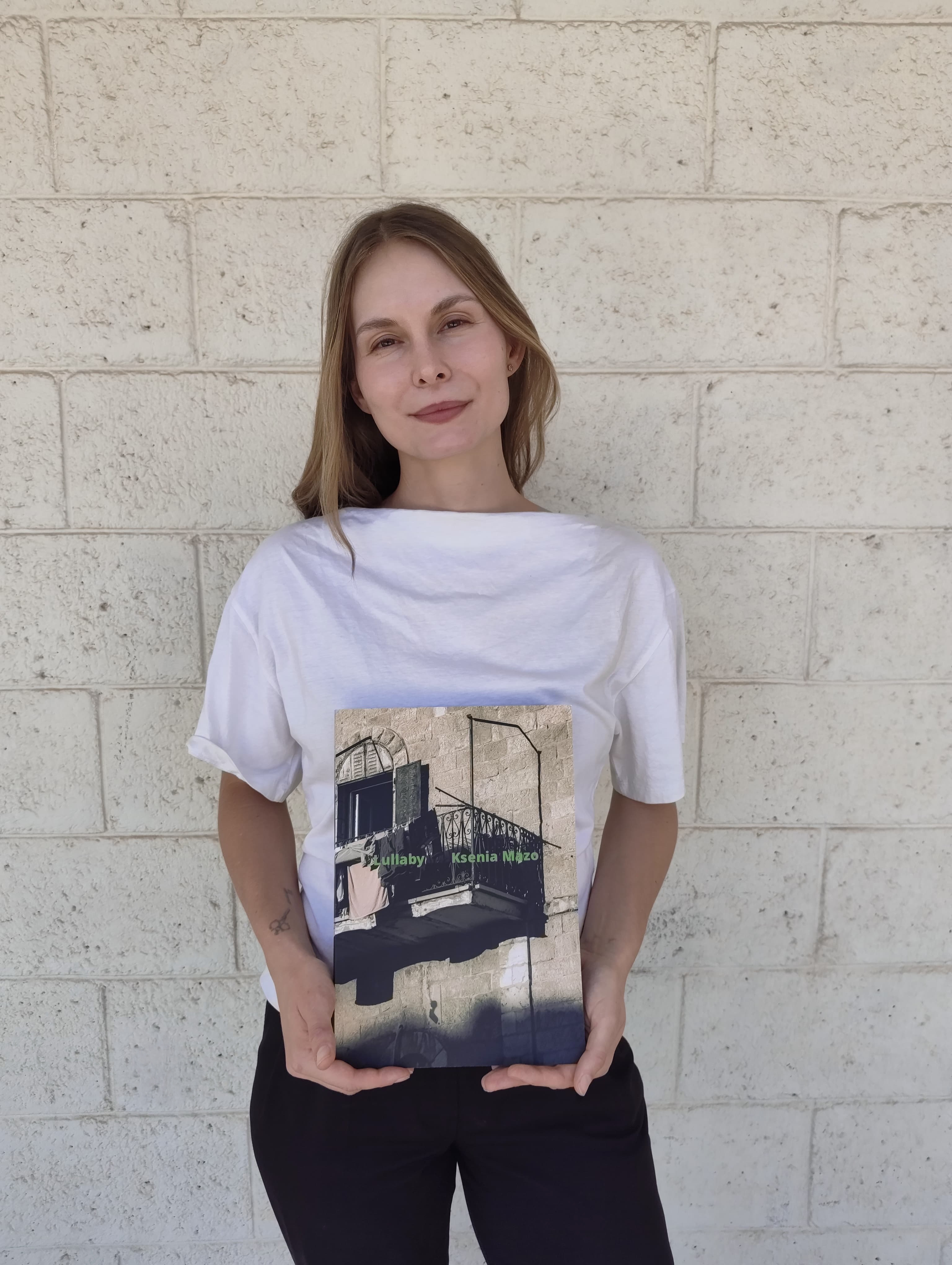 Portrait of Ksenia Mazo holding the Lullaby photobook